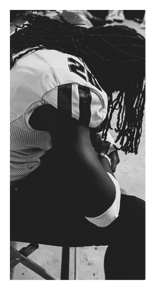 A football player is kneeling on the field, wearing a green jersey and a helmet. AI generated content