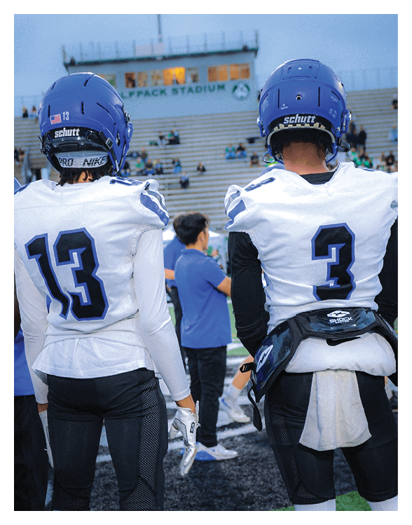 A football player wearing a helmet and white uniform is holding his helmet above his head. AI generated content