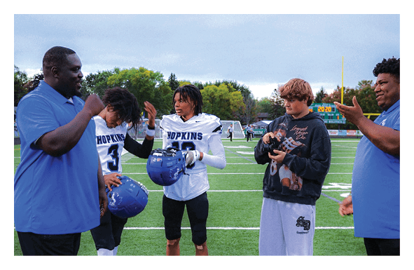 A group of football players wearing headphones and smiling. AI generated content