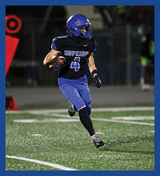 A football player in a white uniform is running with a football in his hand. AI generated content