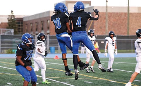 Two men wearing football uniforms are hugging each other on a field. AI generated content