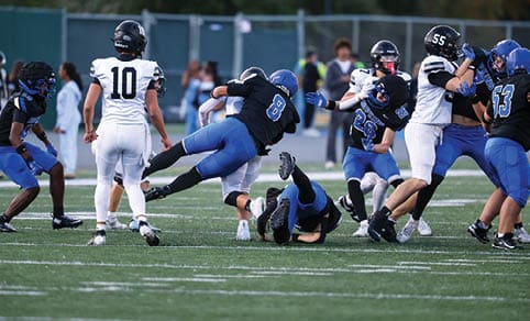Two men wearing football uniforms are hugging each other on a field. AI generated content