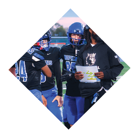 A football player wearing a black jersey with the number 3 kneels on the field. AI generated content