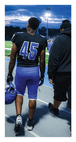 A football player is kneeling on the field, wearing a green jersey and a helmet. AI generated content