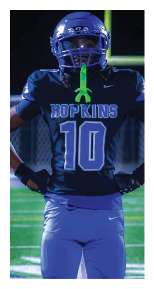A football player is kneeling on the field, wearing a green jersey and a helmet. AI generated content