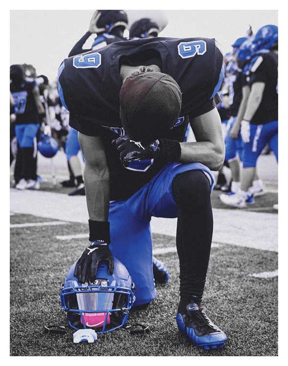 A football player wearing a helmet and white uniform is holding his helmet above his head. AI generated content