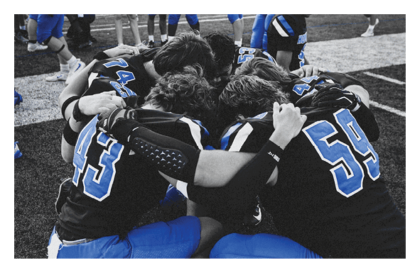 A group of people are kneeling on a field, possibly in a football game. AI generated content