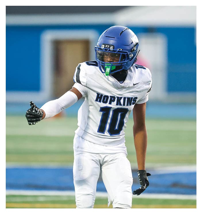 A football game is in progress with players on the field. One player is throwing a football while another player is trying to catch it. The players are wearing uniforms and are actively engaged in the game. AI generated content