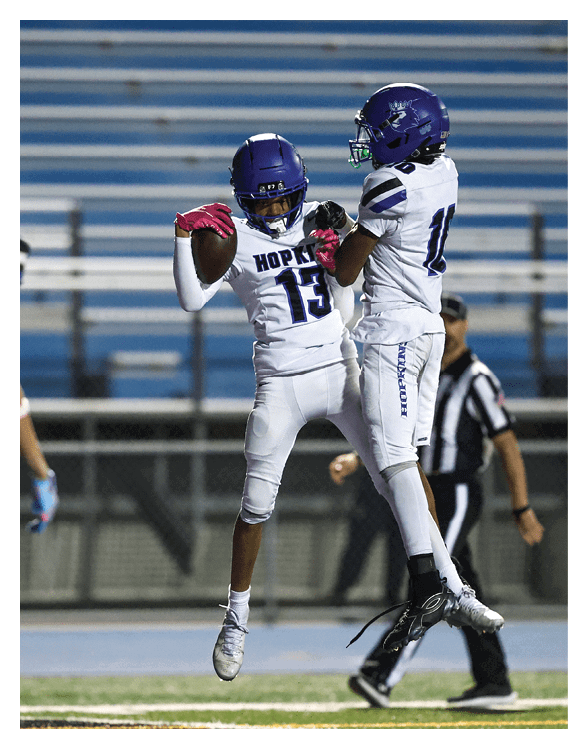 A football player wearing a helmet and white uniform is holding his helmet above his head. AI generated content