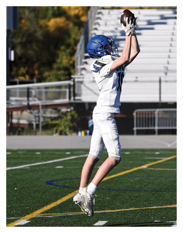 A football player wearing a helmet and white uniform is holding his helmet above his head. AI generated content