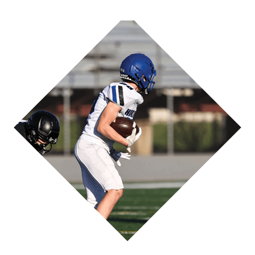 A football player wearing a black jersey with the number 10 sits on the ground with a football helmet on the ground next to him. AI generated content