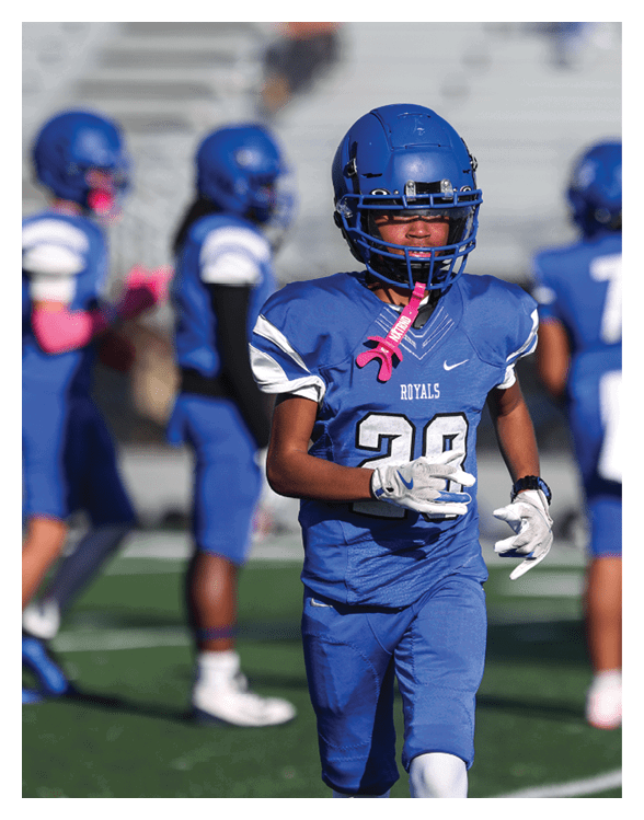 A football player wearing a helmet and white uniform is holding his helmet above his head. AI generated content