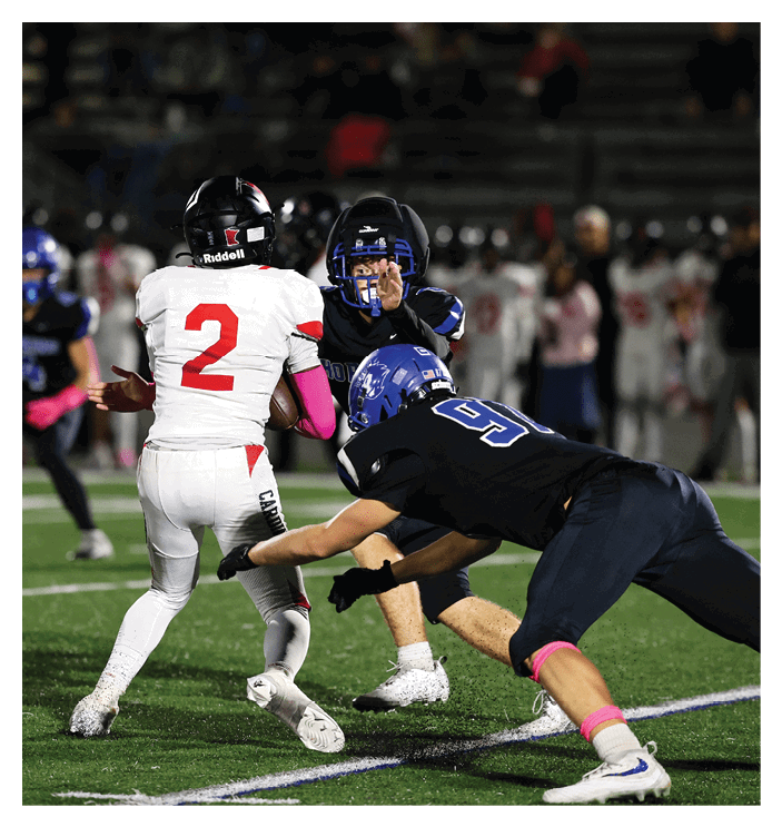 A football game is in progress with players on the field. One player is throwing a football while another player is trying to catch it. The players are wearing uniforms and are actively engaged in the game. AI generated content