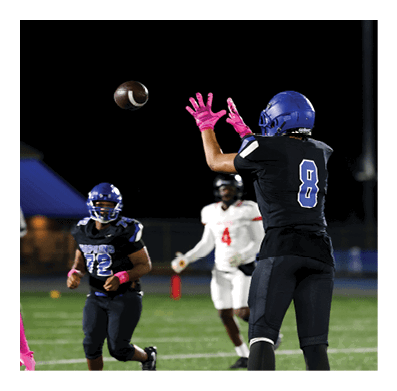 A football player in a white jersey with the number 85 on it is trying to catch a football. AI generated content