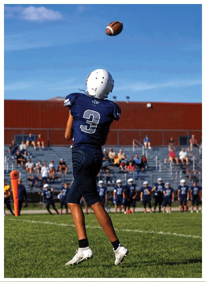 Two football players wearing black jerseys and holding hands. Description generated by AI