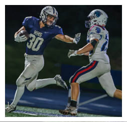Two football players wearing black jerseys and holding hands. Description generated by AI
