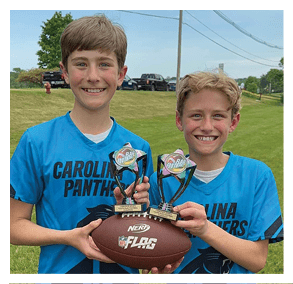 Two football players wearing black jerseys and holding hands. Description generated by AI