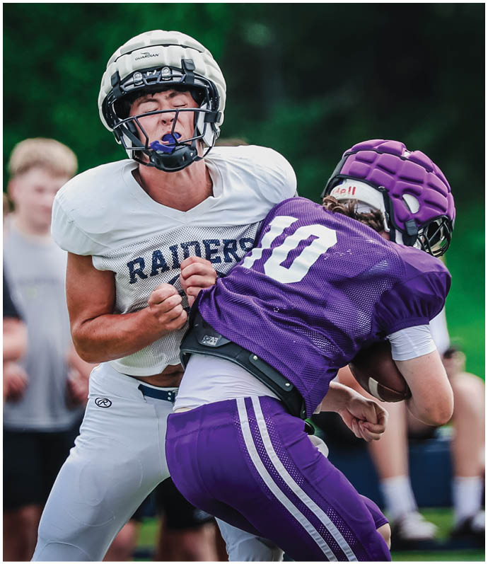 Three football players in blue and white uniforms running on a field. Description generated by AI