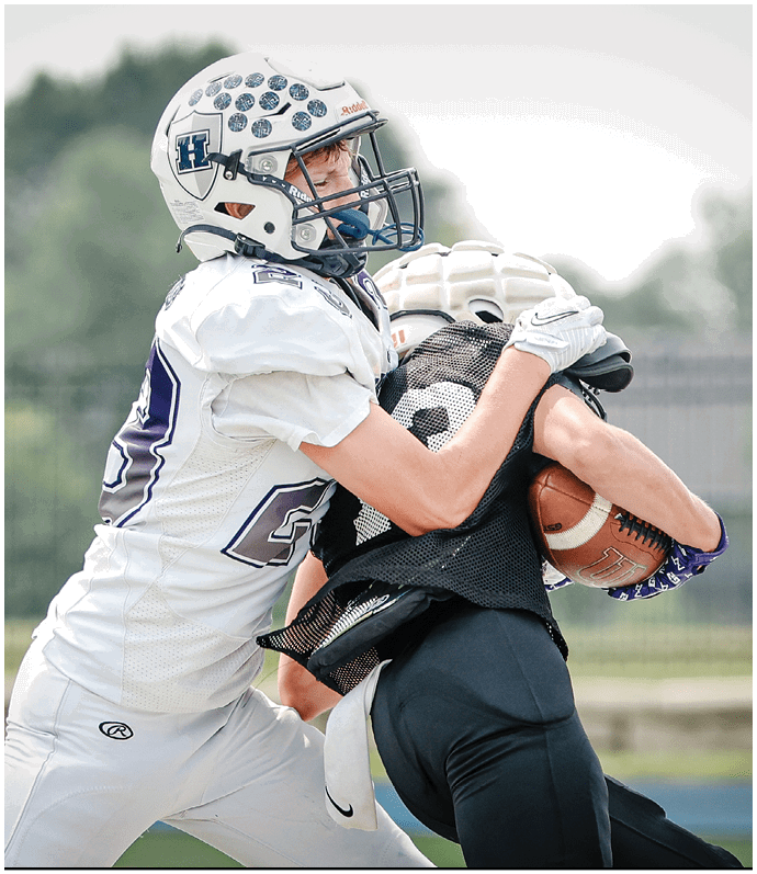 Three football players in blue and white uniforms running on a field. Description generated by AI
