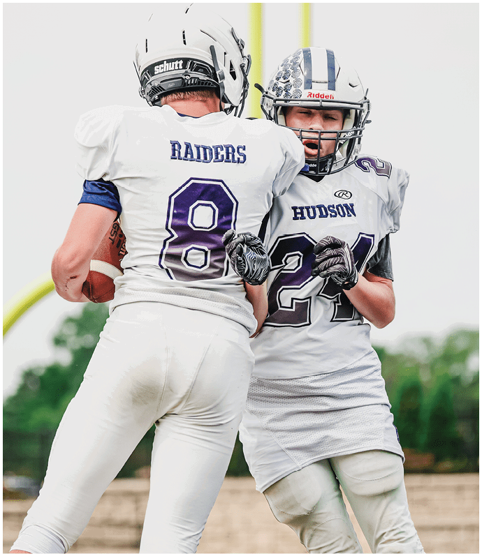 Three football players in blue and white uniforms running on a field. Description generated by AI