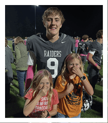Two football players wearing black jerseys and holding hands. Description generated by AI