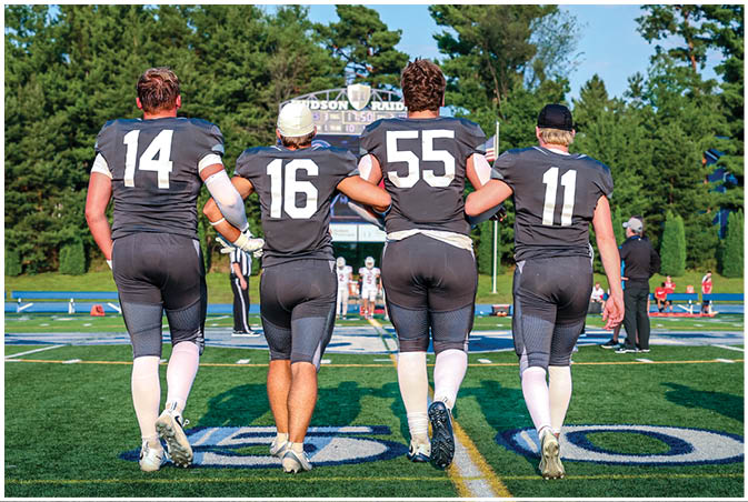 A group of football players wearing black and white uniforms. Description generated by AI