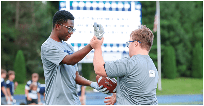 A group of football players wearing black and white uniforms. Description generated by AI