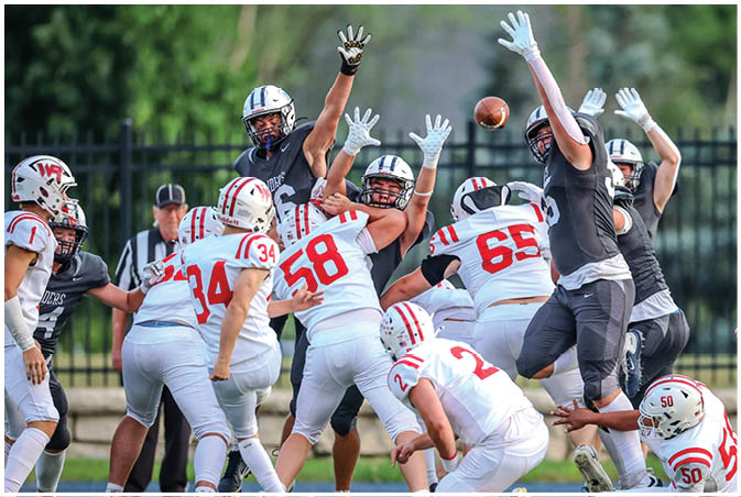 A group of football players wearing black and white uniforms. Description generated by AI