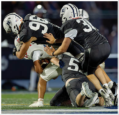 A football game is taking place with a group of men on the field. Description generated by AI