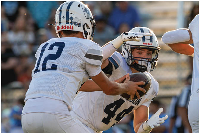 A group of football players wearing black and white uniforms. Description generated by AI