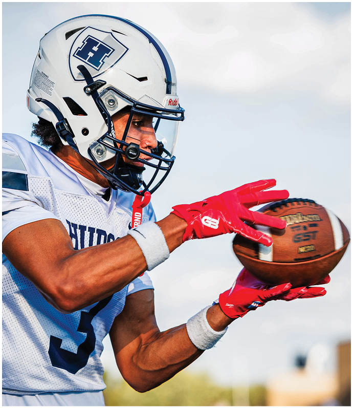 Three football players in blue and white uniforms running on a field. Description generated by AI