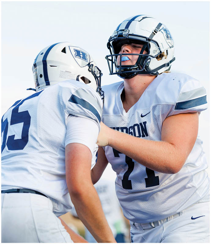 Three football players in blue and white uniforms running on a field. Description generated by AI