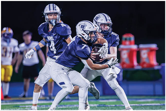 A group of football players wearing black and white uniforms. Description generated by AI