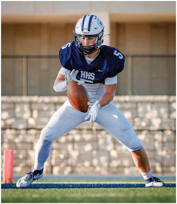 Three football players in blue and white uniforms running on a field. Description generated by AI
