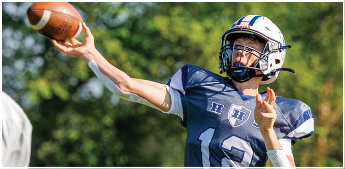 Three football players in blue and white uniforms running on a field. Description generated by AI
