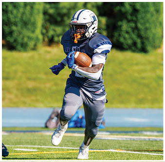 Three football players in blue and white uniforms running on a field. Description generated by AI