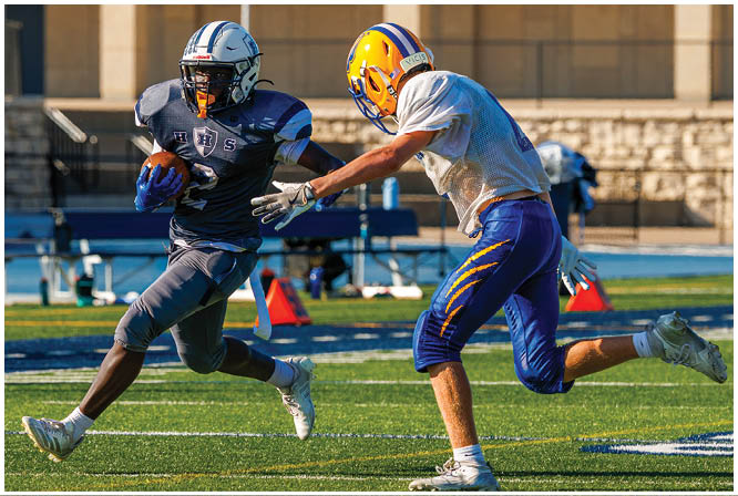 Three football players in blue and white uniforms running on a field. Description generated by AI