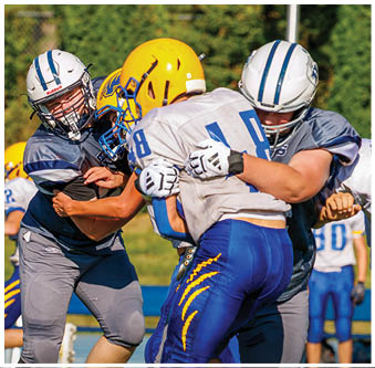 Three football players in blue and white uniforms running on a field. Description generated by AI