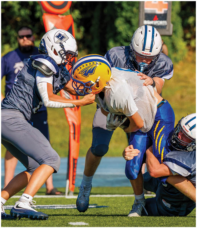 Three football players in blue and white uniforms running on a field. Description generated by AI
