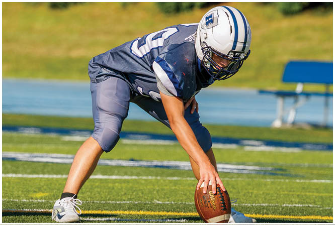 Three football players in blue and white uniforms running on a field. Description generated by AI