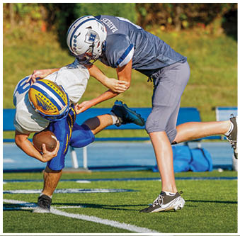 Three football players in blue and white uniforms running on a field. Description generated by AI