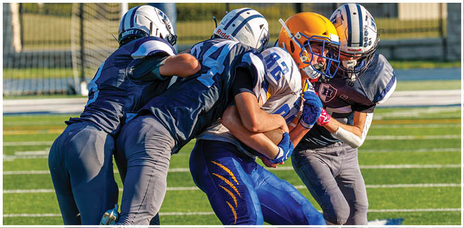 Three football players in blue and white uniforms running on a field. Description generated by AI