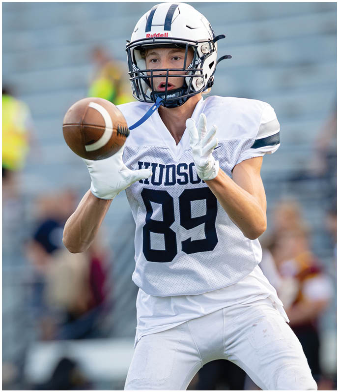 Three football players in blue and white uniforms running on a field. Description generated by AI