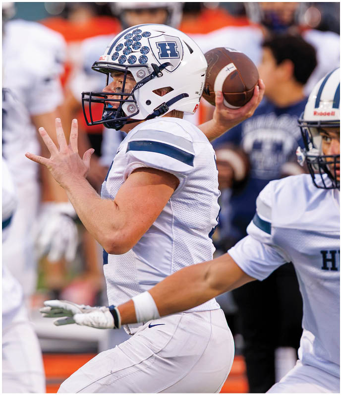 Three football players in blue and white uniforms running on a field. Description generated by AI