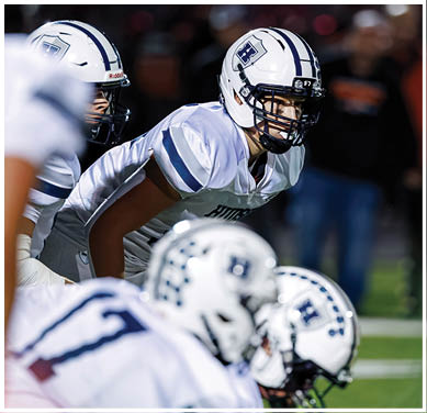 A football game is taking place with a group of men on the field. Description generated by AI
