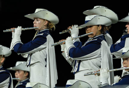 Four people in football uniforms are positioned on a field, appearing ready to start a play during a game. Description generated by AI