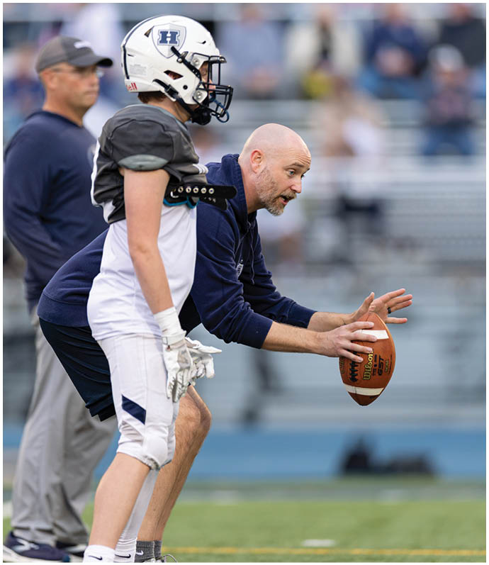 Three football players in blue and white uniforms running on a field. Description generated by AI