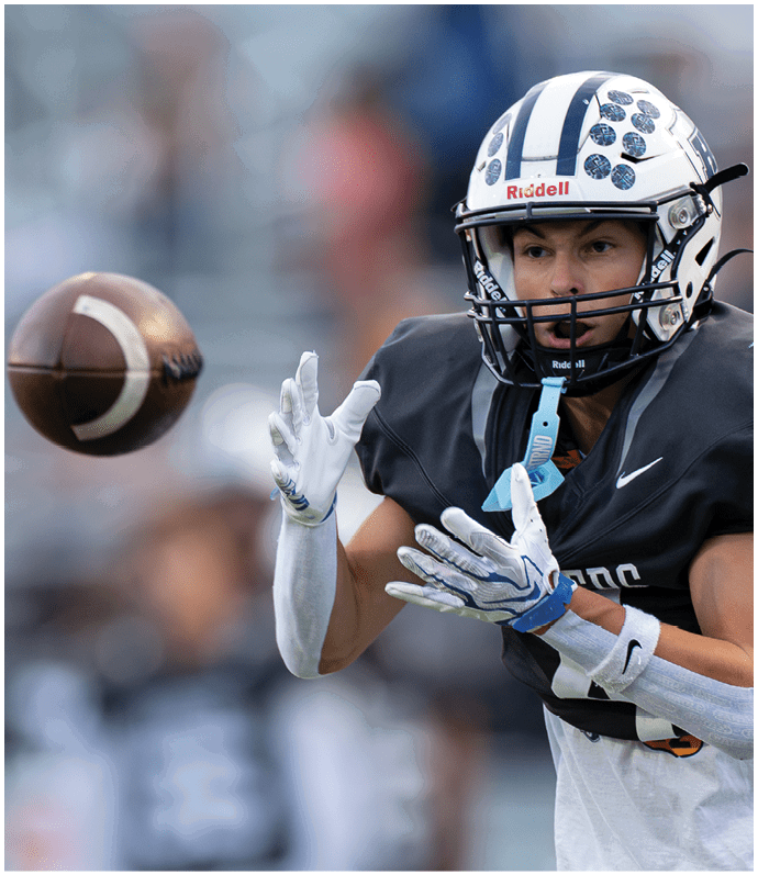 Three football players in blue and white uniforms running on a field. Description generated by AI