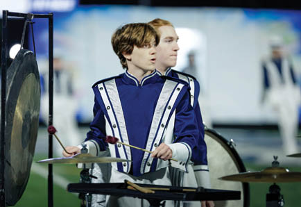 Two adults in football uniforms are actively engaged in a play on a field, with one holding the ball and the other preparing to tackle. Description generated by AI