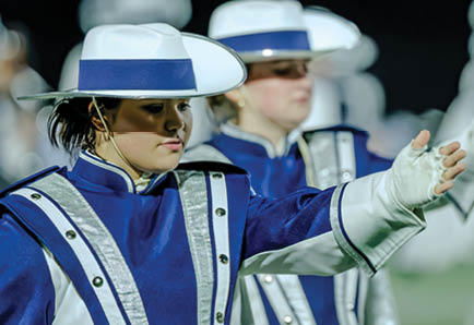 Four people in football uniforms are positioned on a field, appearing ready to start a play during a game. Description generated by AI